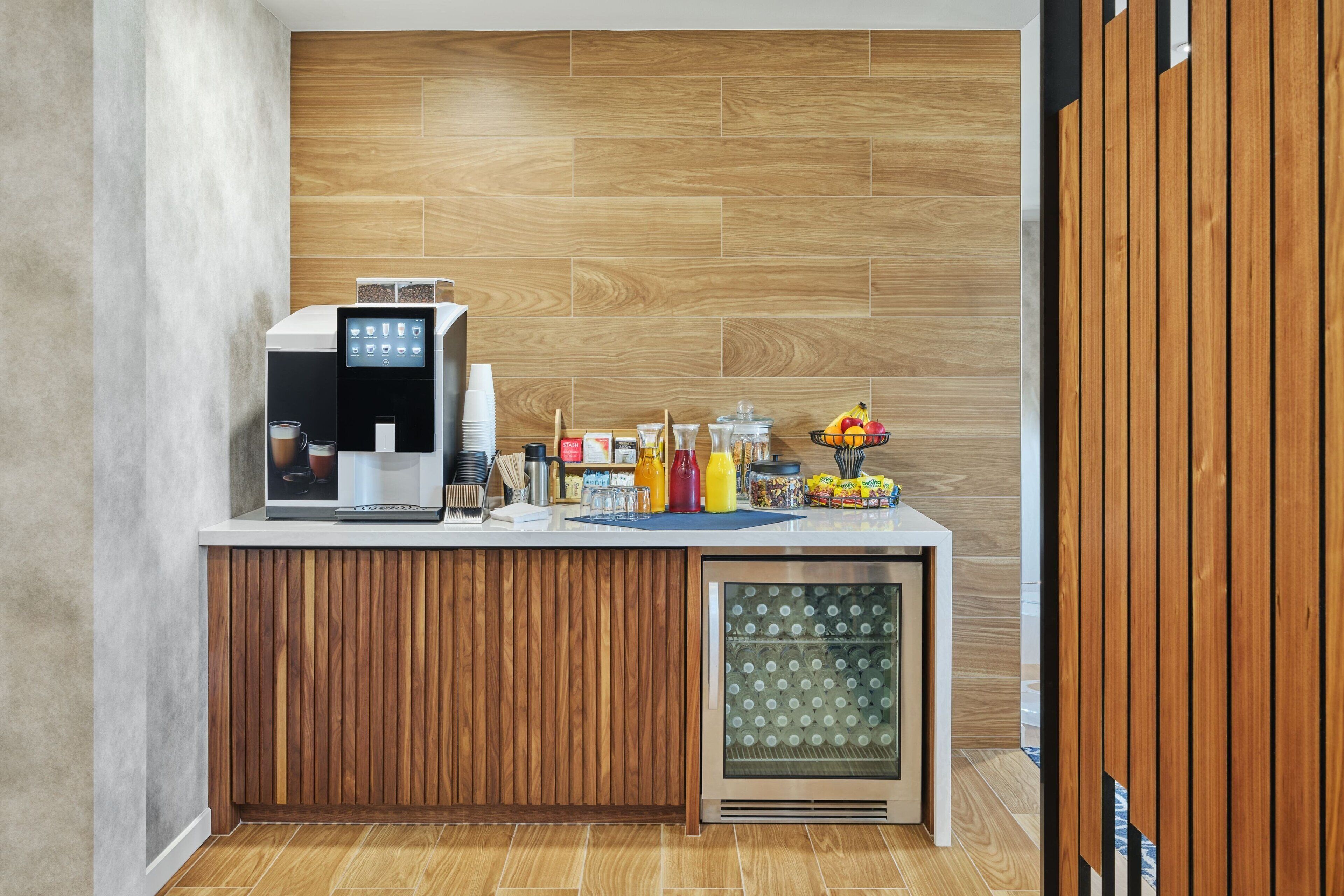 A modern kitchen area with a coffee machine, a refrigerator, and various kitchen items on the counter.