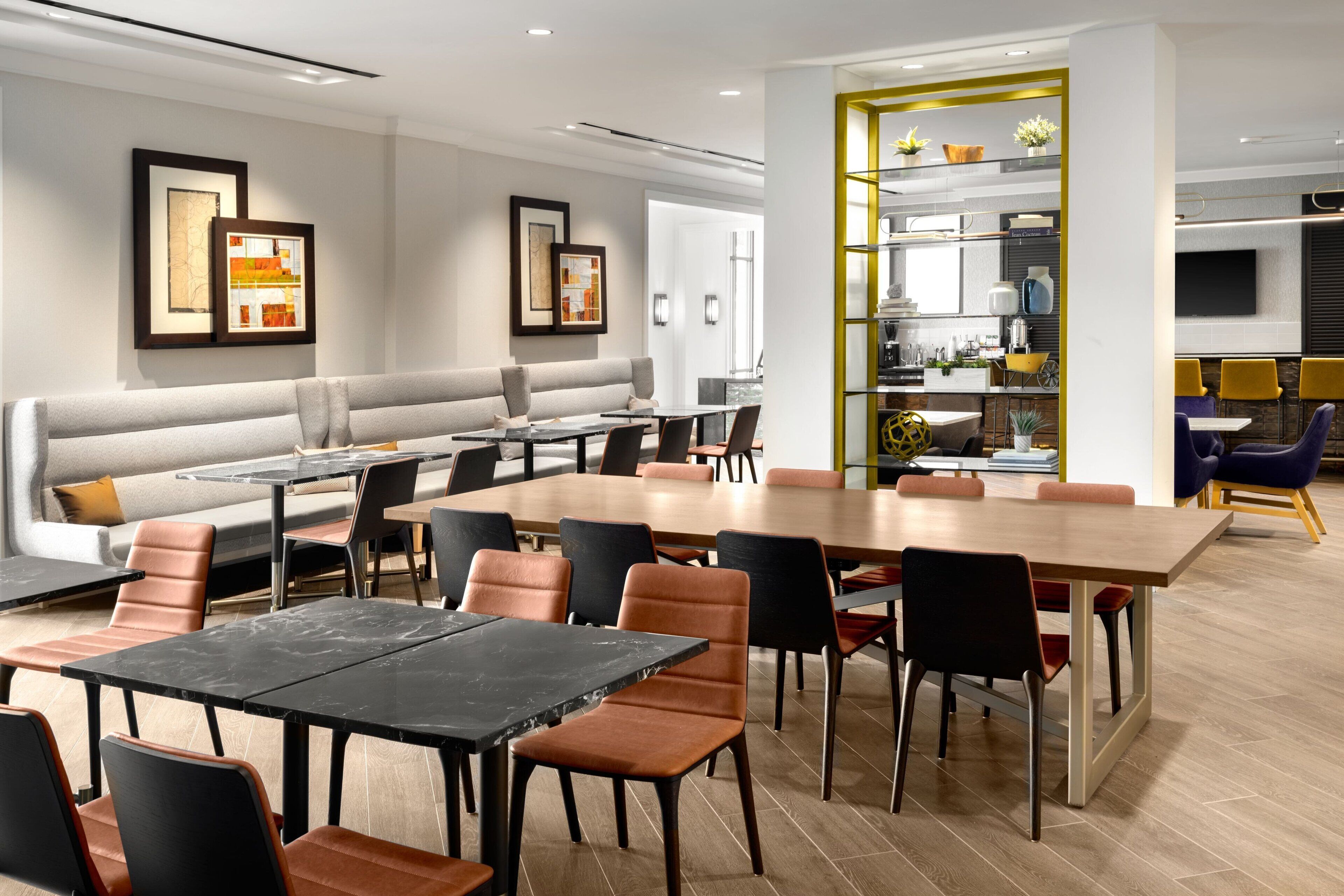 A modern dining area with a long wooden table, multiple chairs, and a sofa.