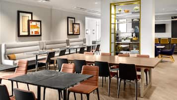 A modern dining area with a long wooden table, multiple chairs, and a sofa.