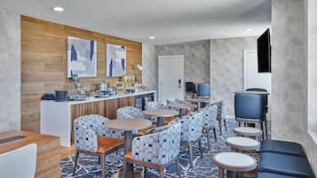 Un moderno vestíbulo de hotel con zona de bar, espacios de asiento y obras de arte en las paredes.