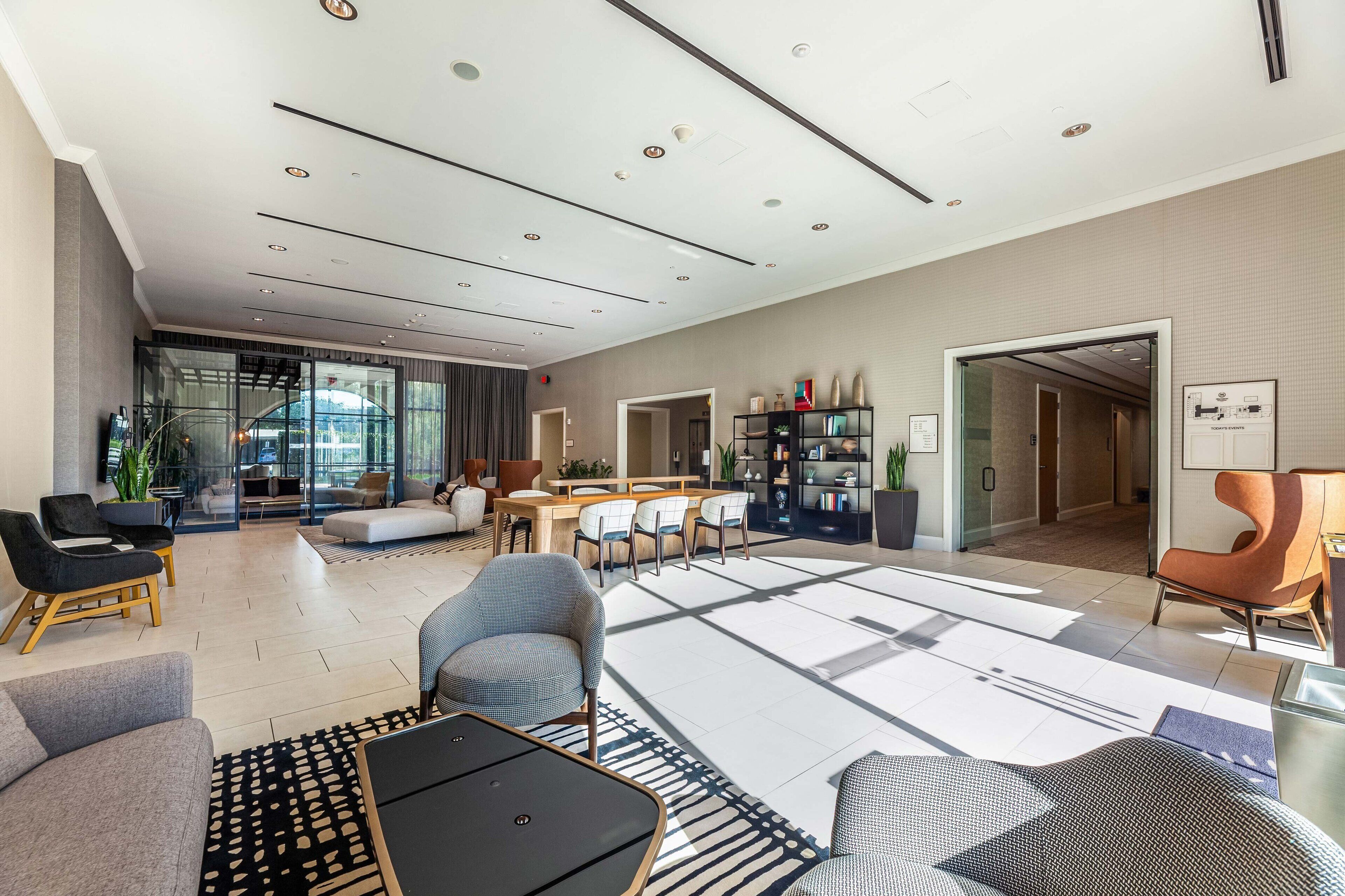 A spacious living area with a modern design, featuring a sofa, chairs, a coffee table, and a dining area with a table and chairs.
