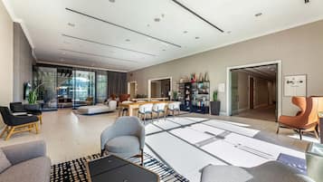 Ampla sala de estar com design moderno, apresentando um sofá, poltronas, uma mesa de centro e um espaço de jantar com mesa e cadeiras.