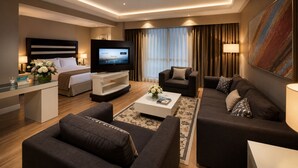 A modern hotel room with a bed, a TV, a sofa, a coffee table, and a desk. - ADM Grand Hotel (Istanbul)