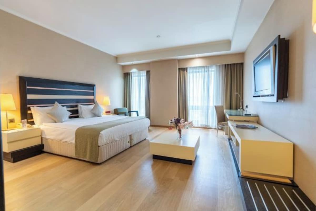 Une chambre d’hôtel équipée d’un lit, d’une table de chevet, d’un bureau, d’une chaise et d’un téléviseur fixé au mur.