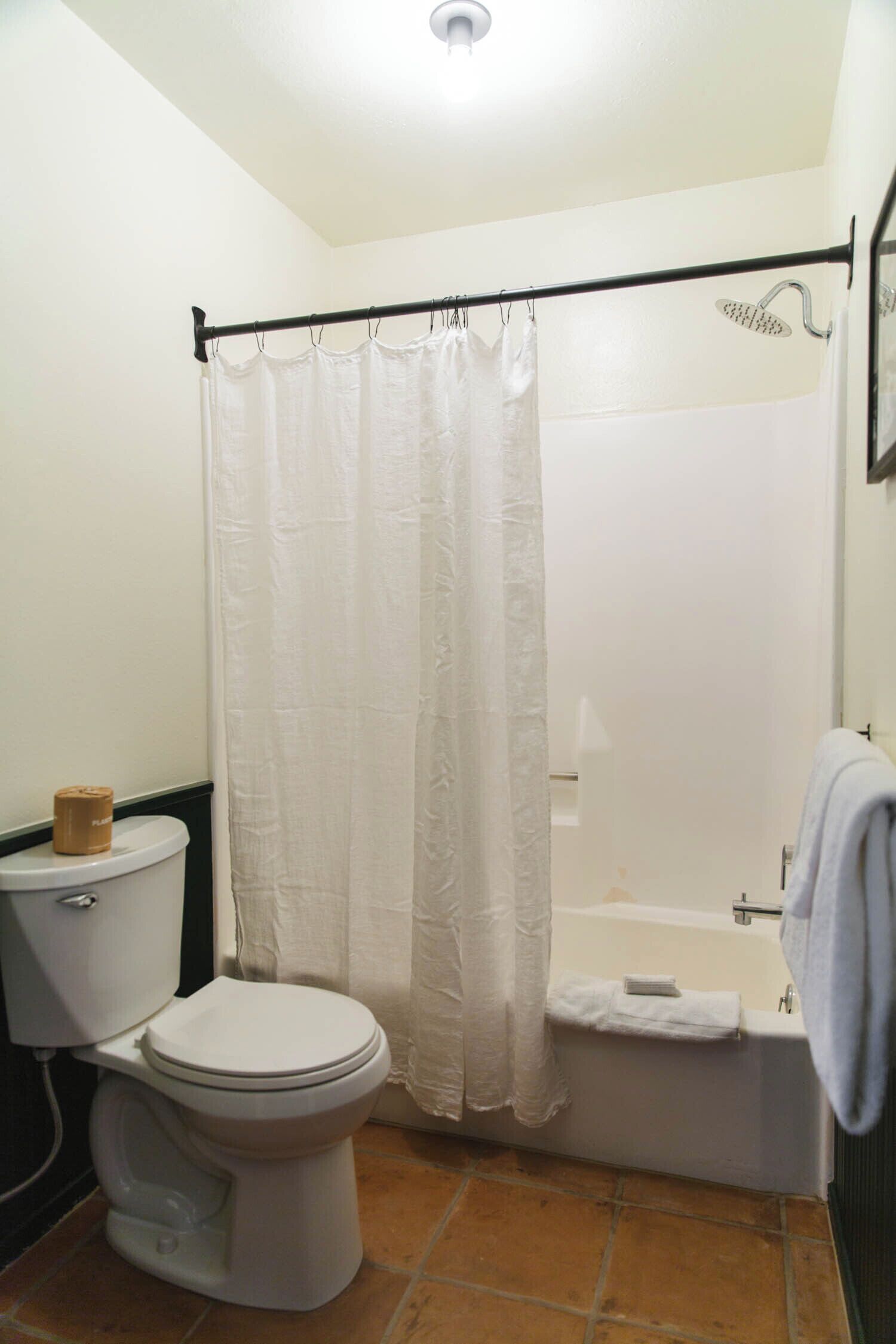 A bathroom with a toilet, a shower curtain, and a bathtub.
