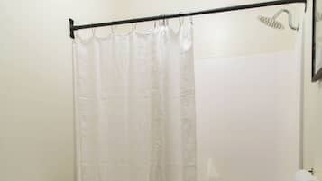 A bathroom with a toilet, a shower curtain, and a bathtub.