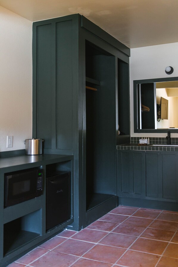 A kitchen with dark cabinetry, a microwave, and a stove. - Hummingbird Inn of Ojai (Ojai)