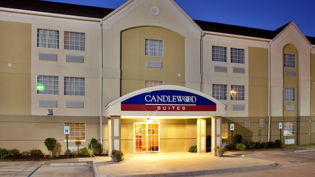 A hotel with a prominent "CANDLEWOOD SUITES" sign, multiple windows, and a well-lit entrance. - Candlewood Suites Lake Charles - Sulphur by IHG (Sulphur)