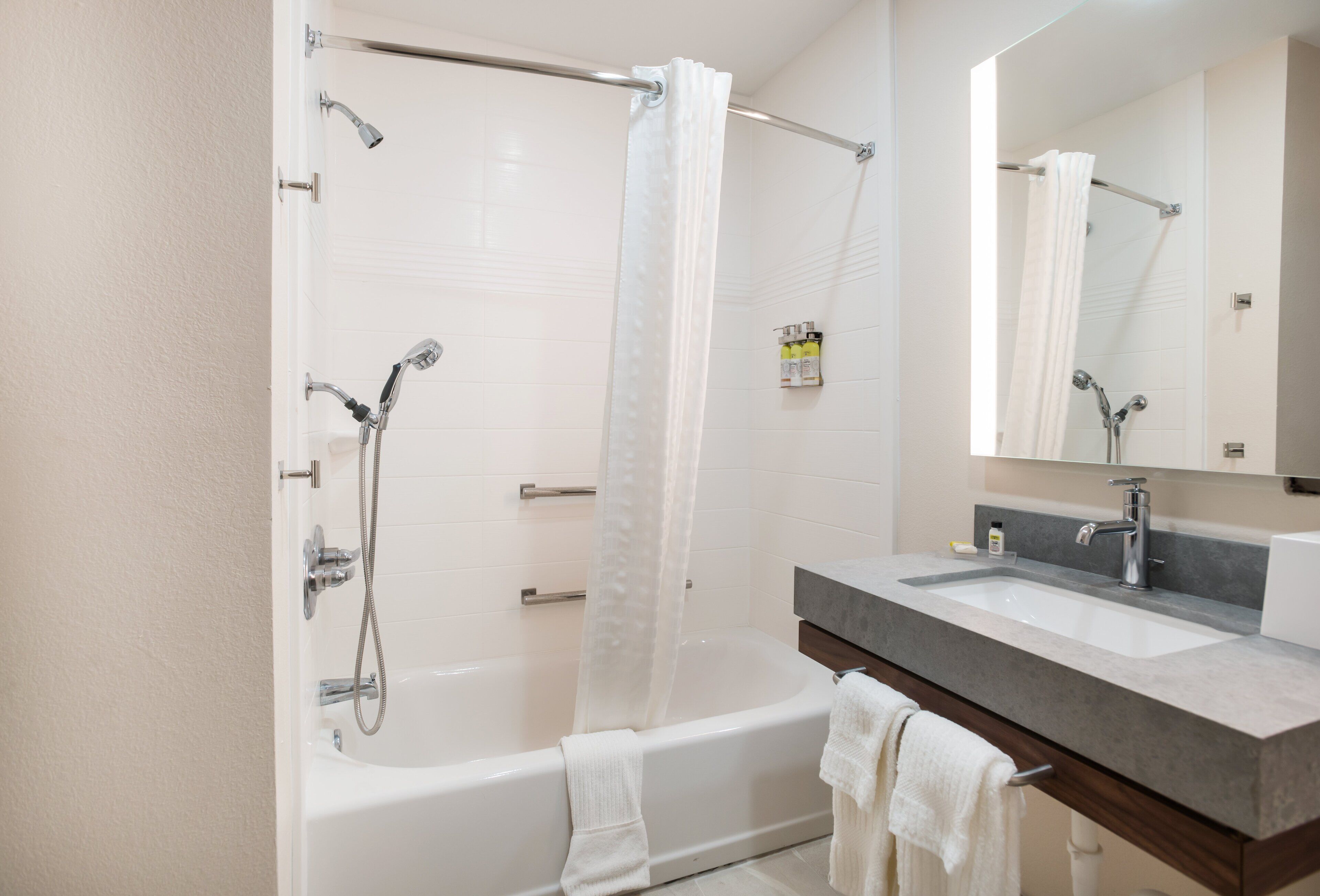 A modern bathroom with a bathtub, shower, and sink.