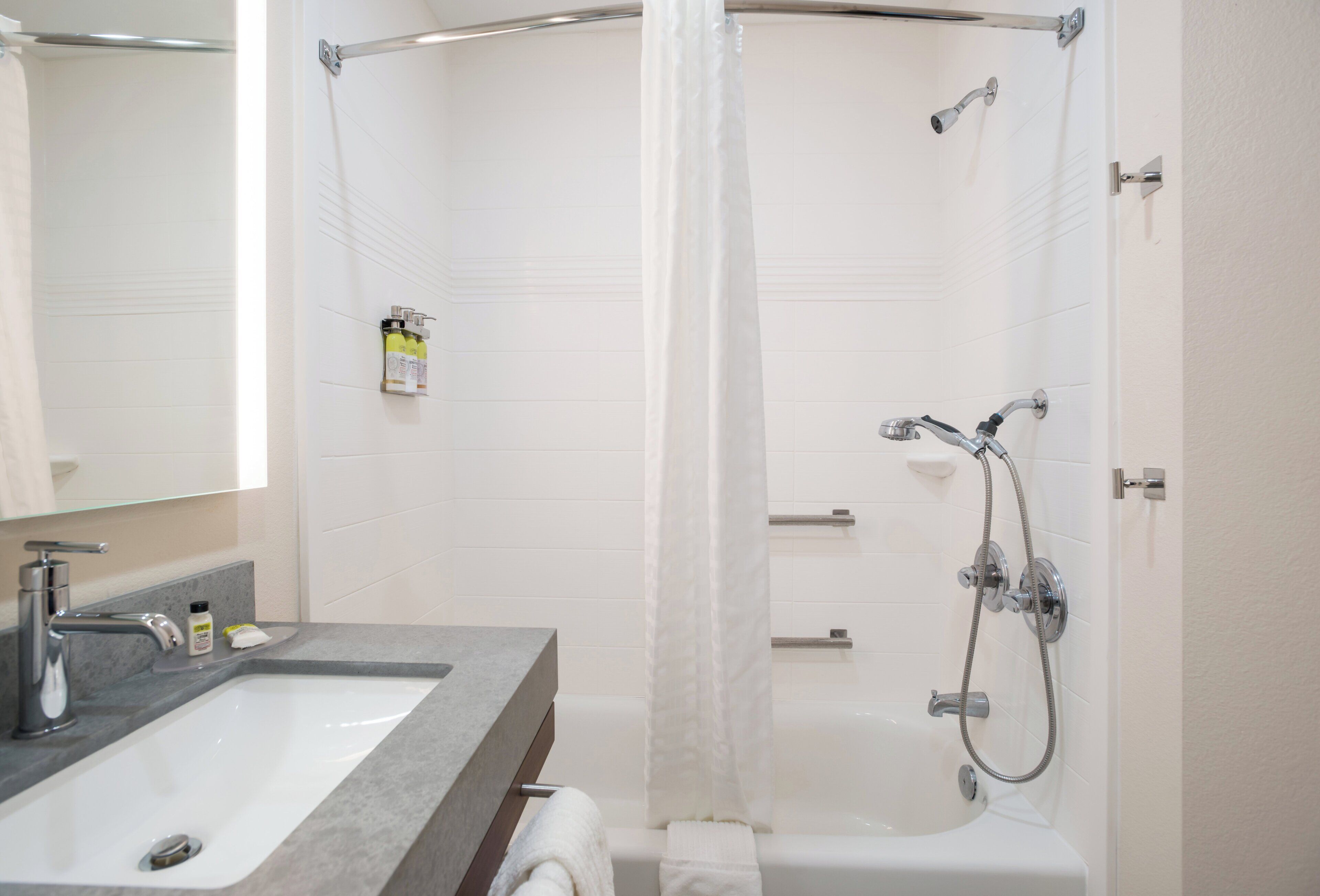 A modern bathroom with a shower, a sink, and a mirror.