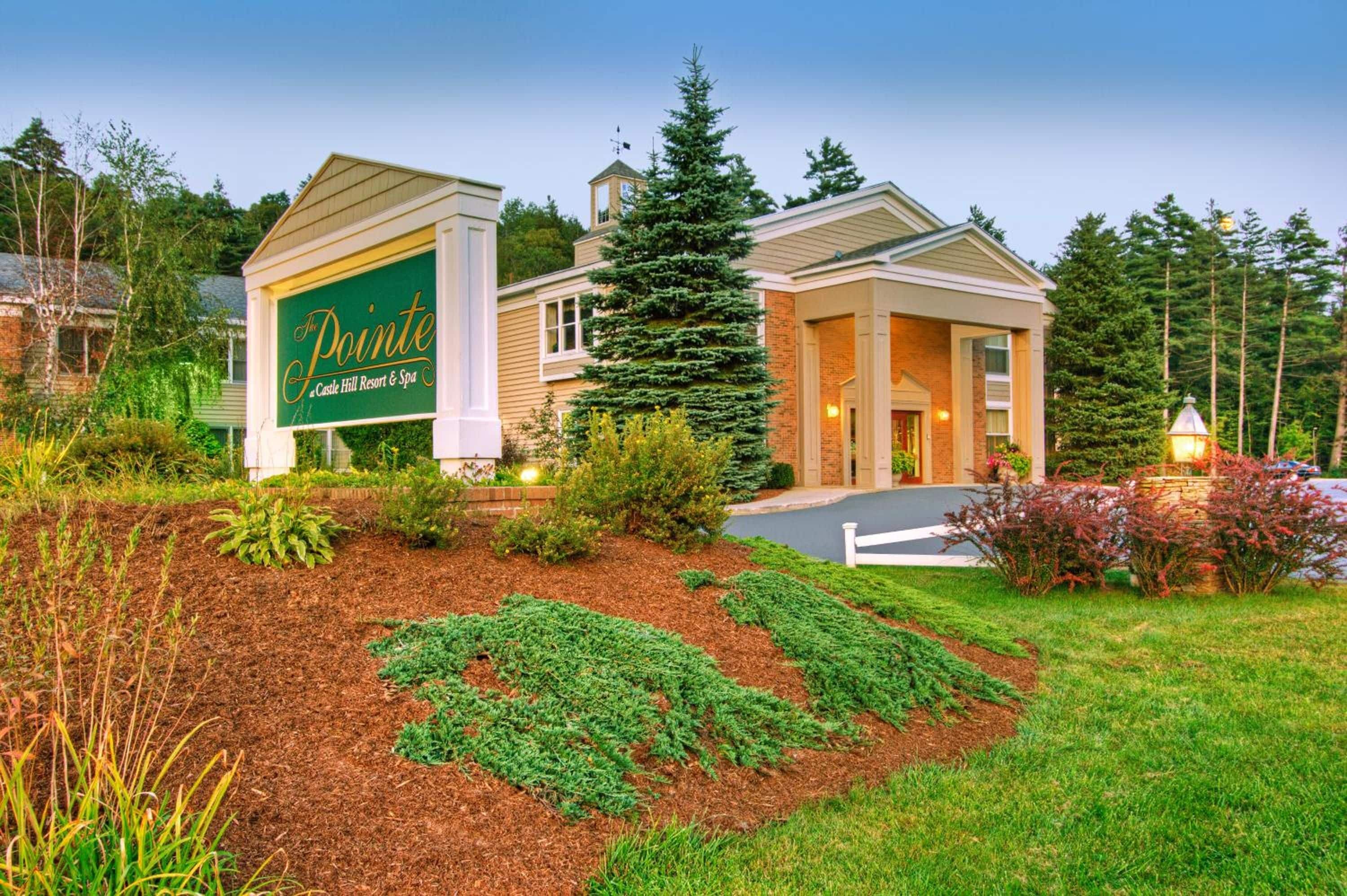 Een resortgebouw met een bordje voor 'The Pointe Castle Hill Resort & Spa' en een verzorgde tuin.