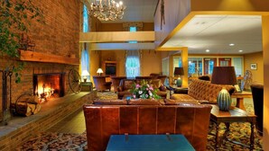 A spacious lobby with a fireplace, leather seating, and a chandelier. - Pointe at Castle Hill Resort (Cavendish)