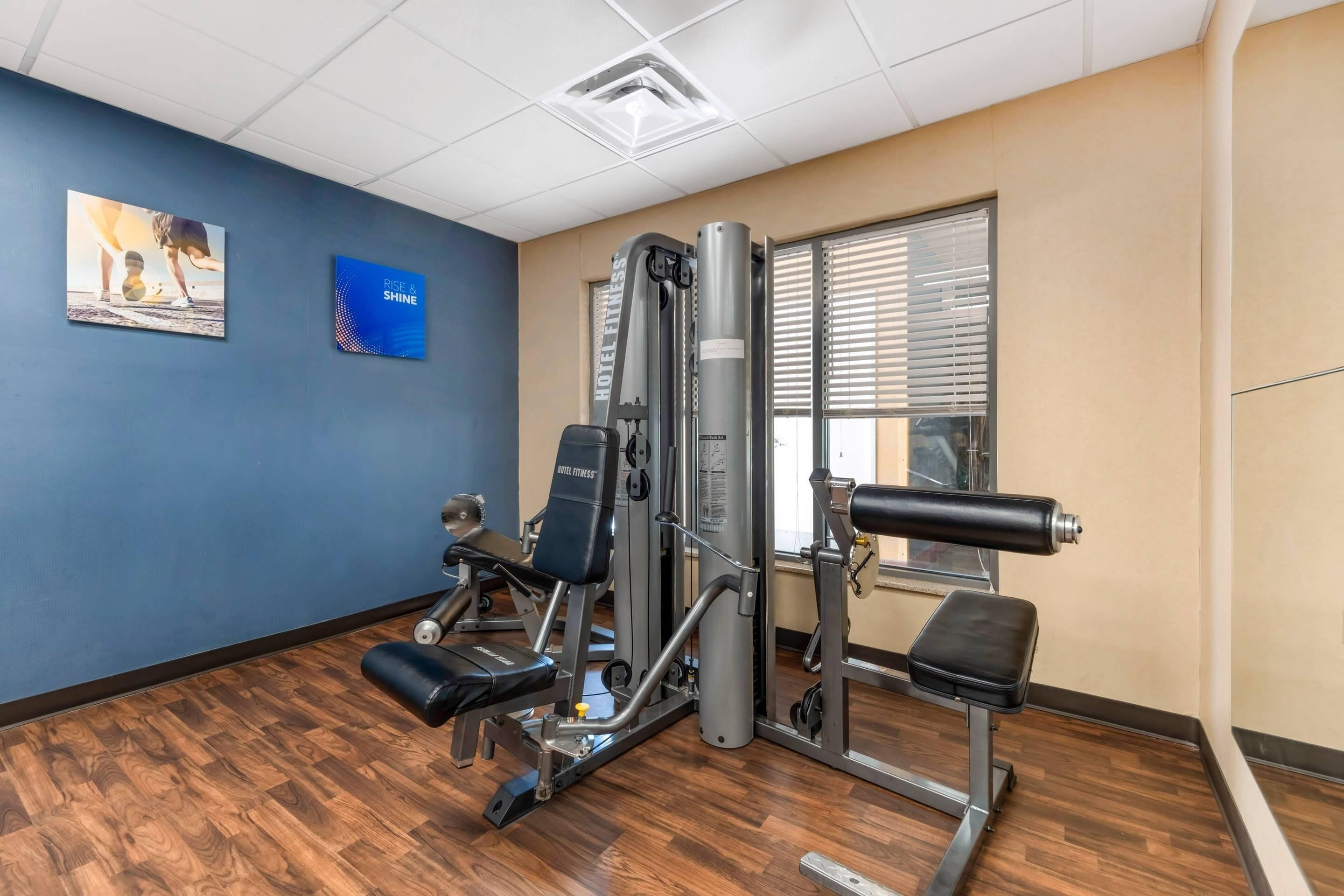 A gym with exercise machines, a bench, and a motivational poster on the wall.