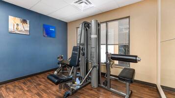 A gym with exercise machines, a bench, and a motivational poster on the wall.