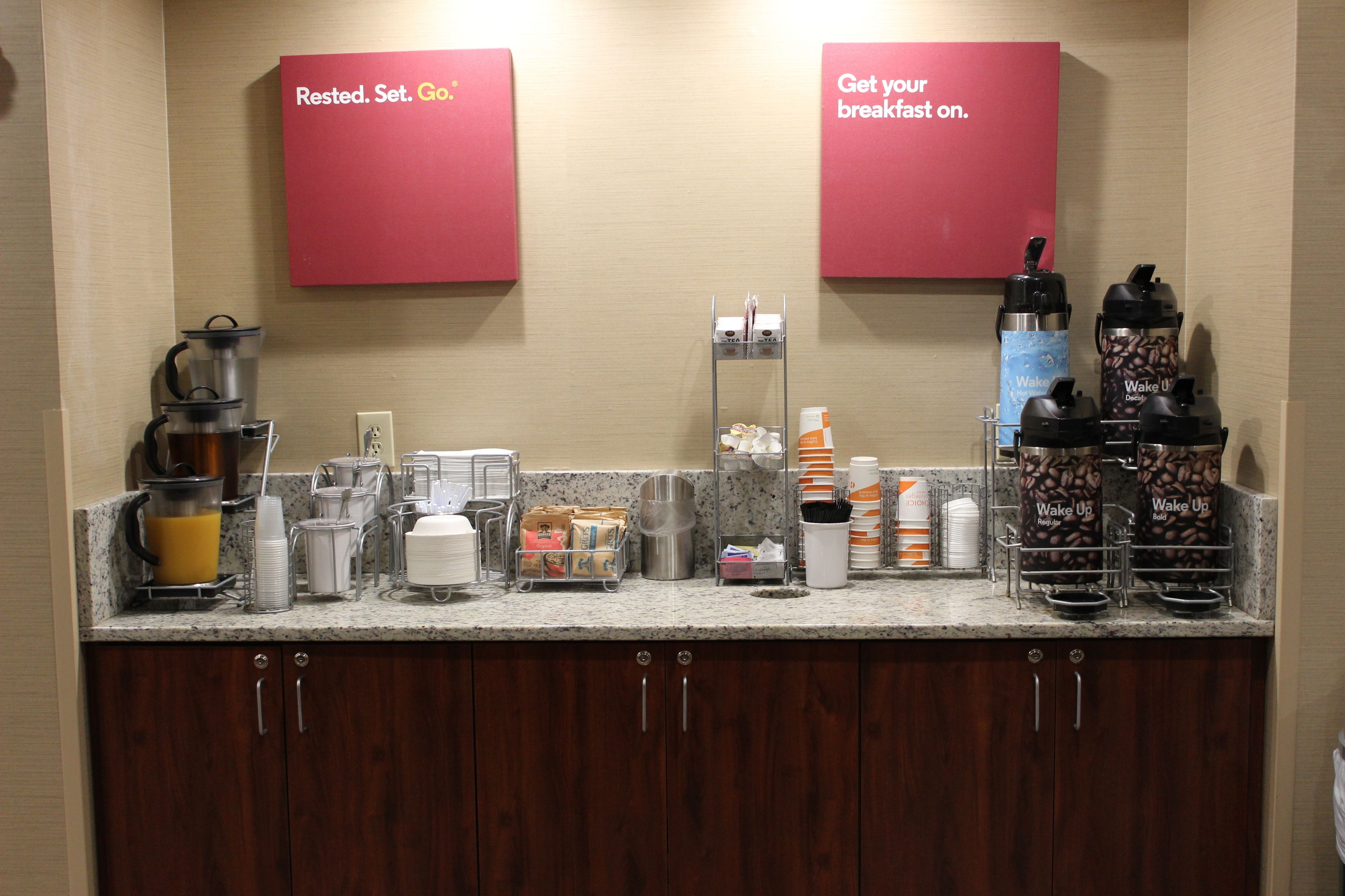 A breakfast bar with coffee makers, a coffee grinder, and various breakfast items.