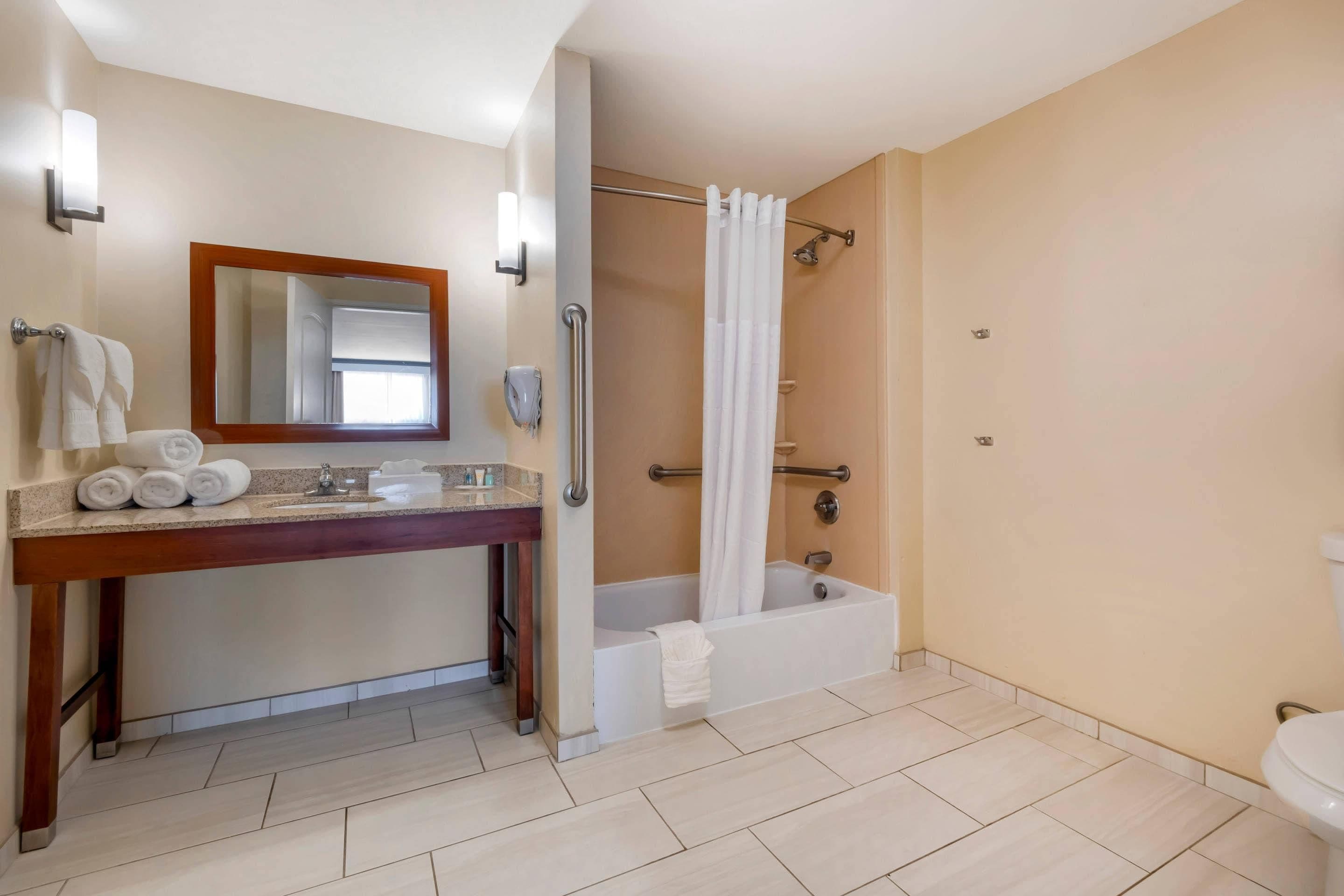 Un baño con tocador de madera, bañera y ducha con cortina.