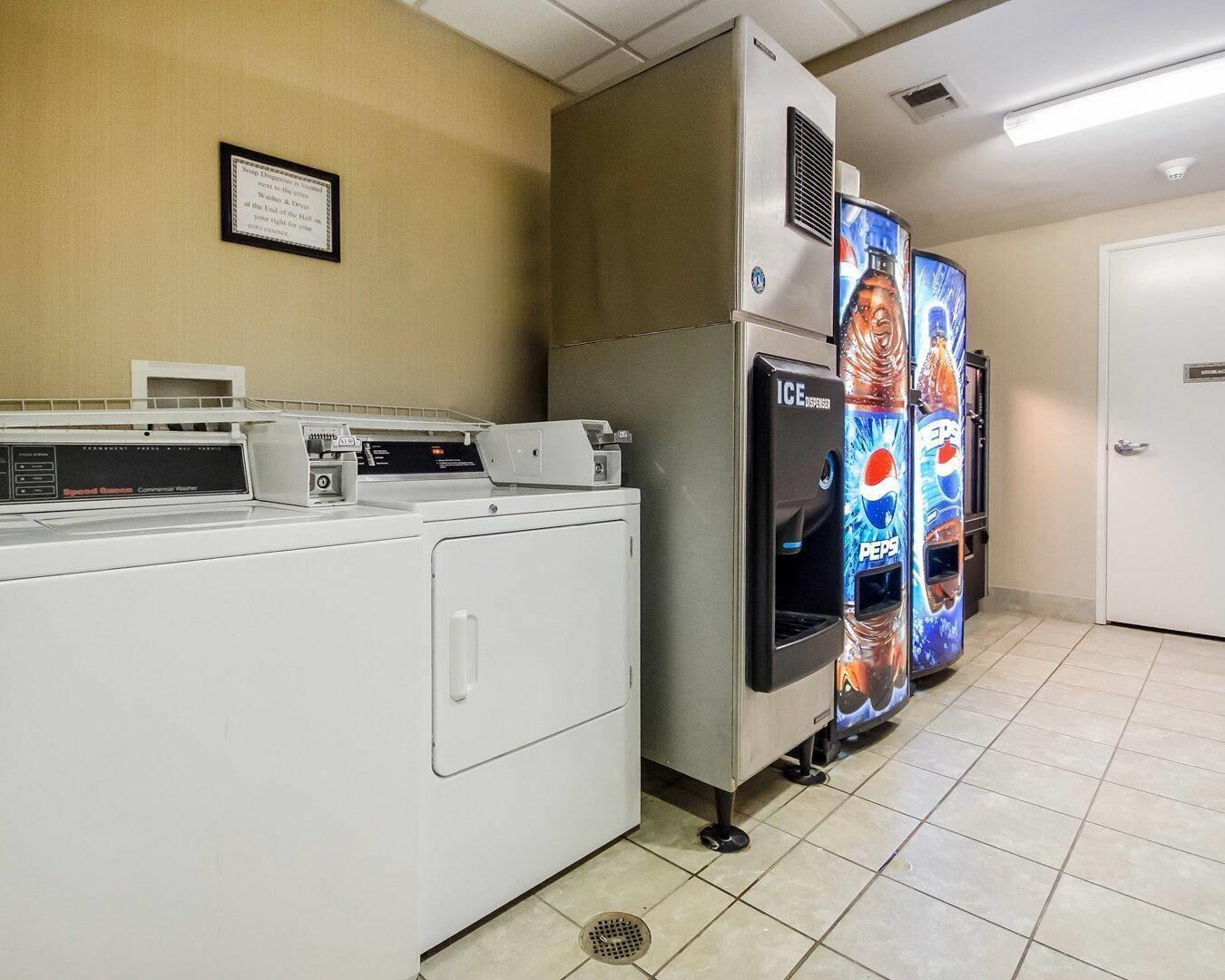 A laundry area with a commercial washer, a dryer, and a vending machine.