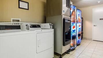 A laundry area with a commercial washer, a dryer, and a vending machine.