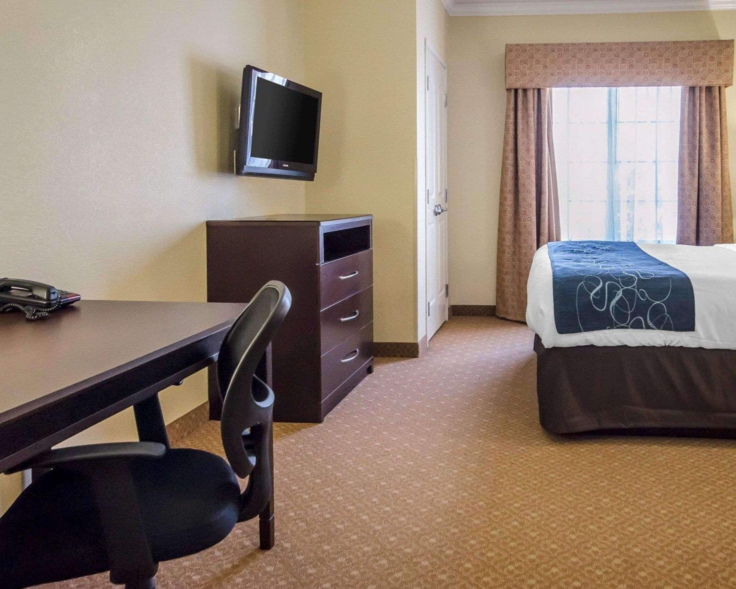 A hotel room with a bed, a desk with a chair, a television, and a wardrobe.