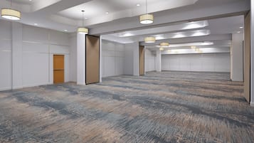 A spacious, modern hotel room with a large carpeted area, recessed ceiling lights, and a wooden door.
