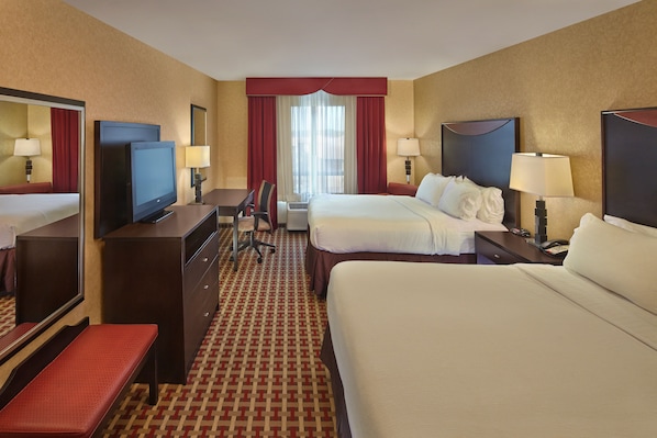 Une chambre d’hôtel avec un grand lit, un bureau avec une chaise, une télévision et un miroir.