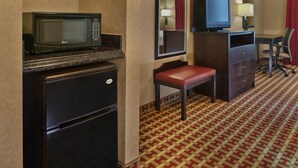 Une chambre d’hôtel compacte dotée d’une kitchenette, comprenant un four à micro-ondes, un réfrigérateur et un petit bureau avec une chaise.