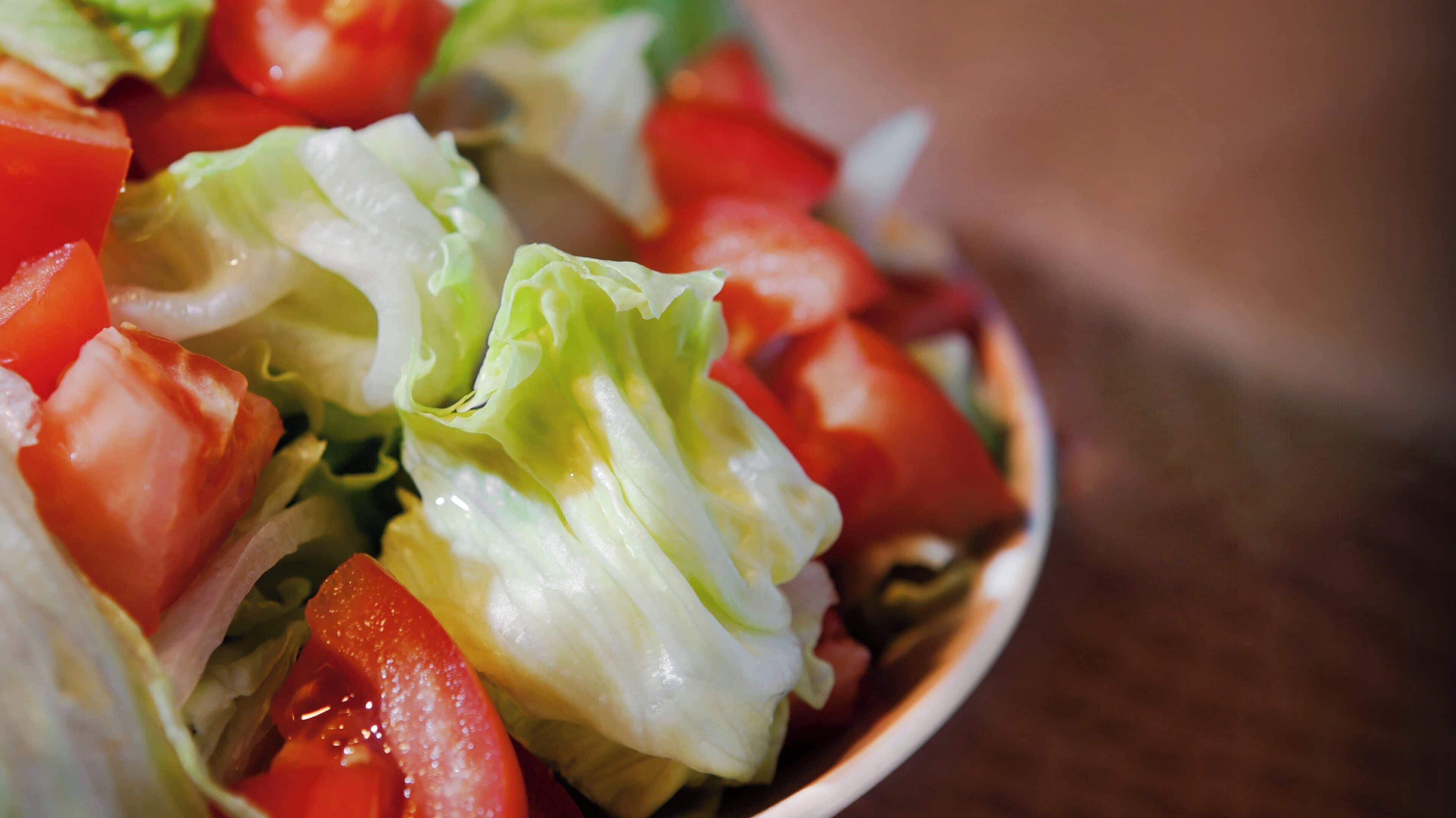 A bowl of salad with lettuce and tomatoes.