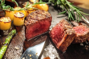 A steak with a knife, roasted potatoes, and asparagus on a wooden surface. - InterContinental Chengdu Century City by IHG (Chengdu)