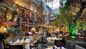 An indoor dining area with tables set for guests, surrounded by lush greenery and traditional architectural elements. - InterContinental Chengdu Century City by IHG (Chengdu)