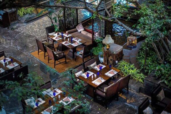 An indoor dining area with tables set for four, surrounded by greenery and a small water feature. - InterContinental Chengdu Century City by IHG (Chengdu)