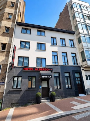 A hotel with a reception area, multiple windows, and a sign indicating it's Hotel Albero.