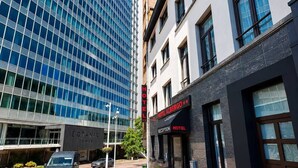 Un hotel con área de recepción, un cartel que indica que es un hotel y un edificio moderno con fachada de vidrio al fondo.