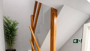 A staircase with white steps, wooden handrails, and a green emergency exit sign. - Hotel Albergo (Brussels)