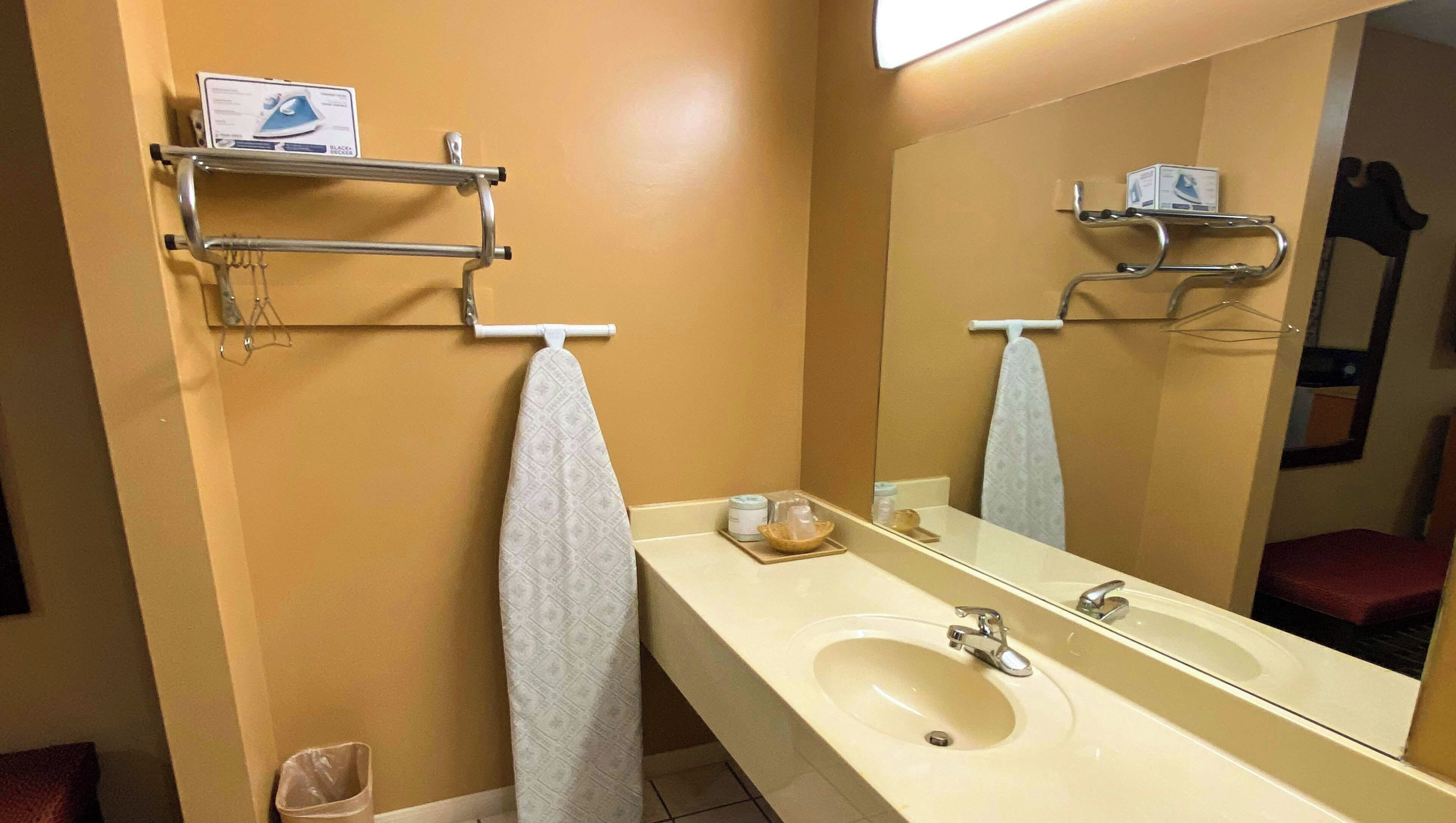 Un baño con un lavabo color crema, un espejo y un perchero con una toalla.