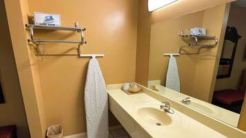Un baño con un lavabo color crema, un espejo y un perchero con una toalla.