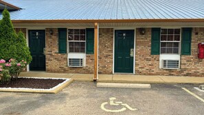 A building with numbered doors, air conditioning units, and a parking space marked with a wheelchair accessibility symbol.