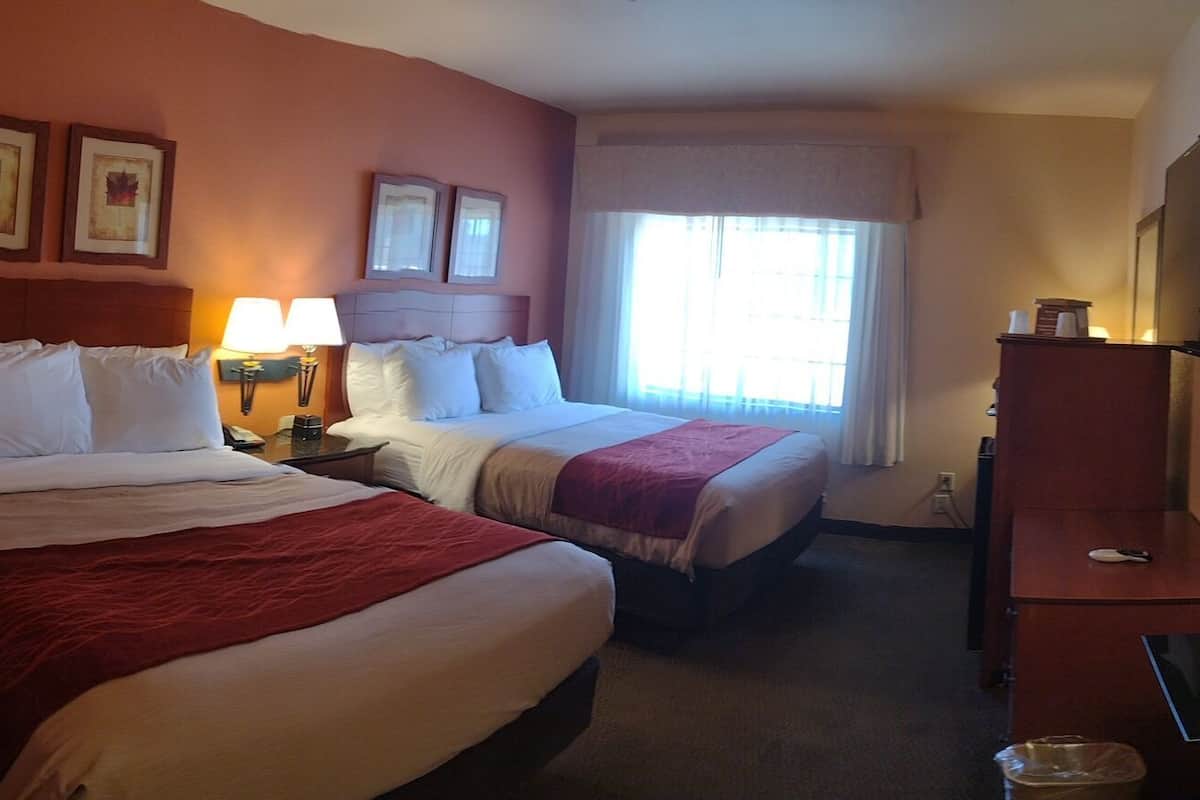Une chambre d’hôtel avec un grand lit, un lit plus petit, une chaise, une table et un téléviseur.
