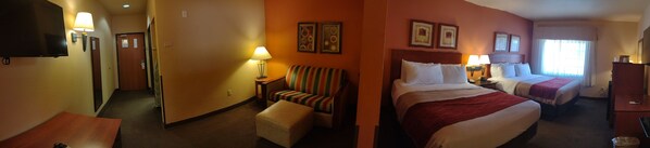 A hotel room with a large bed, a smaller bed, a chair, a table, and a TV. - Hotel Ruidoso - Midtown (Ruidoso)