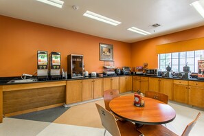 A kitchen with wooden cabinets, a round dining table, and a microwave. - Hotel Ruidoso - Midtown (Ruidoso)