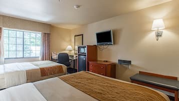 A hotel room with two beds, a desk with a computer, a television, a lamp, and a bench.