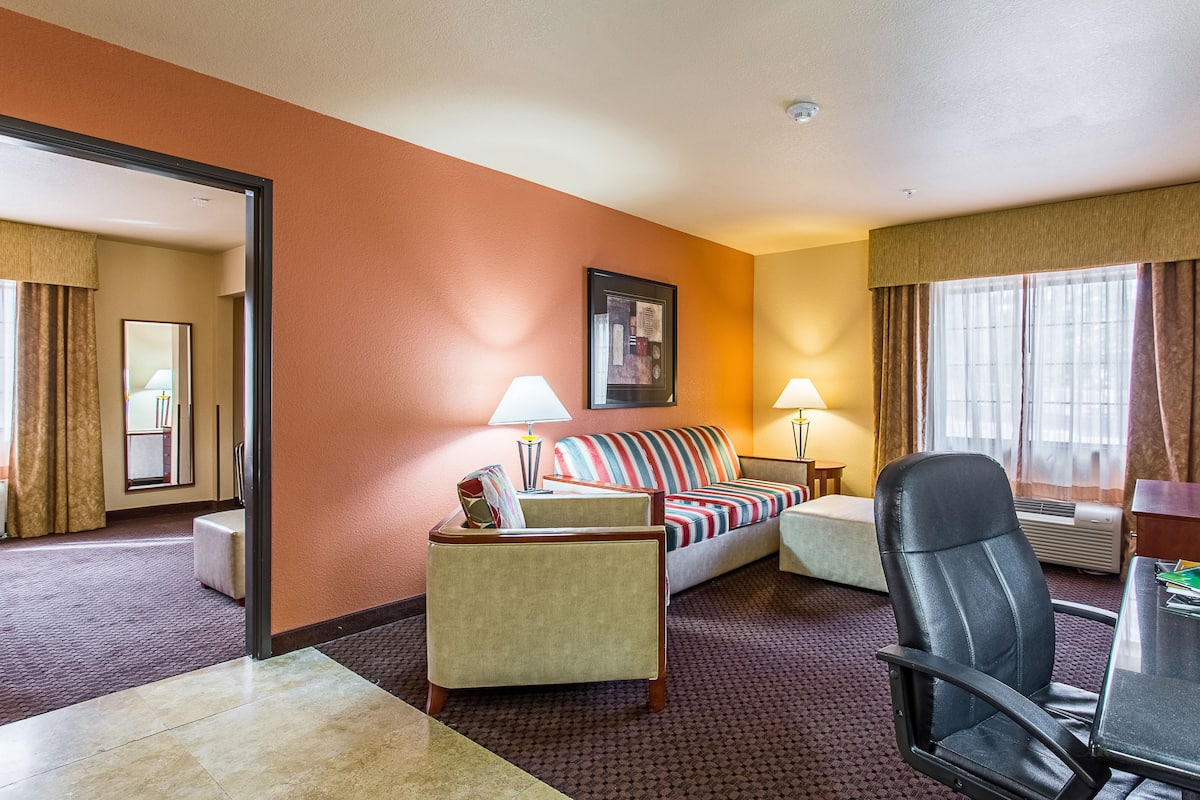 Une chambre d’hôtel avec un canapé, un fauteuil et une petite table avec une lampe.