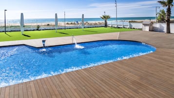 Una piscina al aire libre, sombrillas, sillones reclinables de piscina