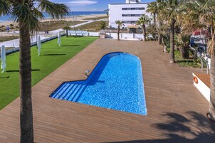 Una piscina al aire libre, sombrillas, tumbonas
