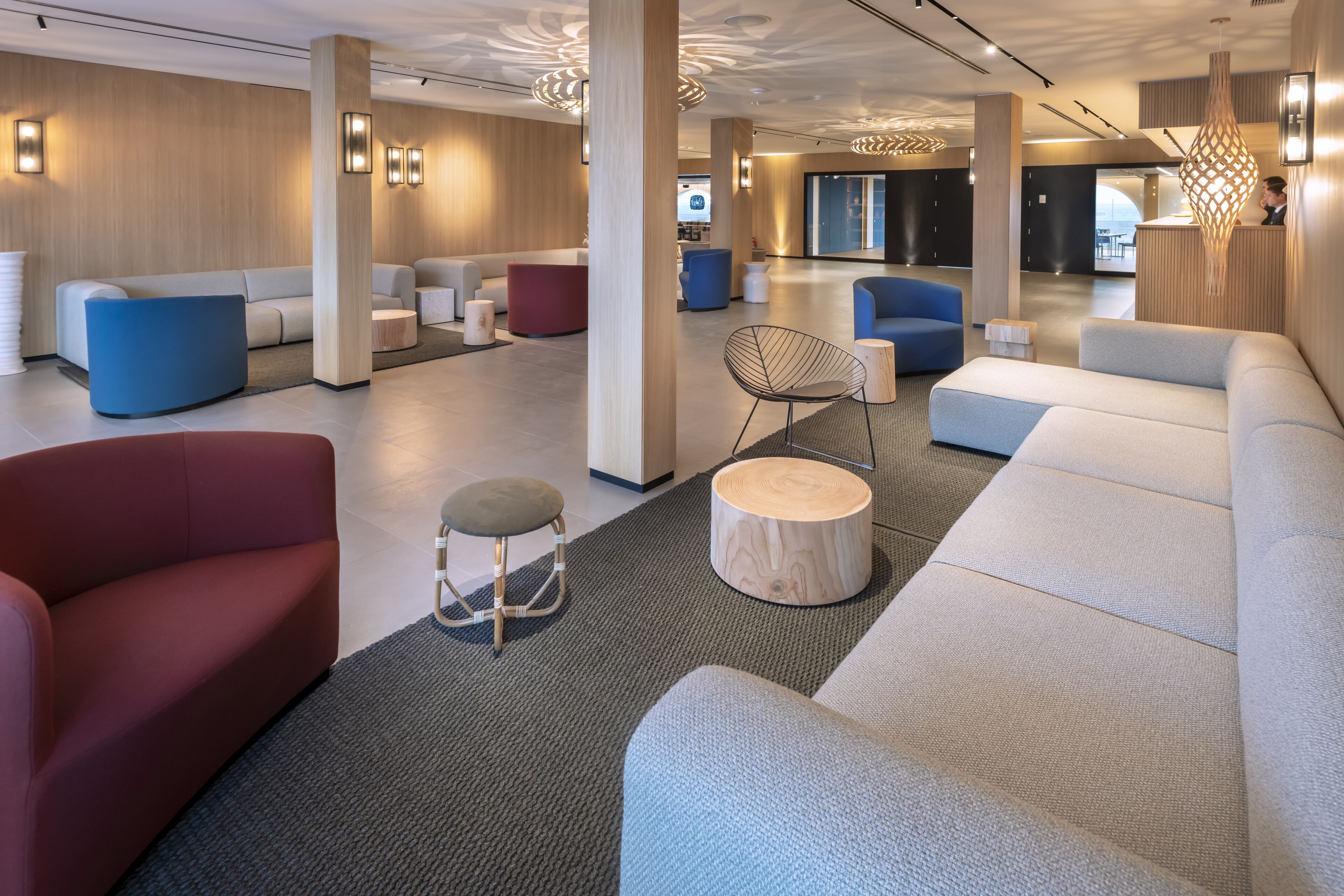 Een moderne hotellobby met een ruim zithoek, een receptiebalie en een groot raam.