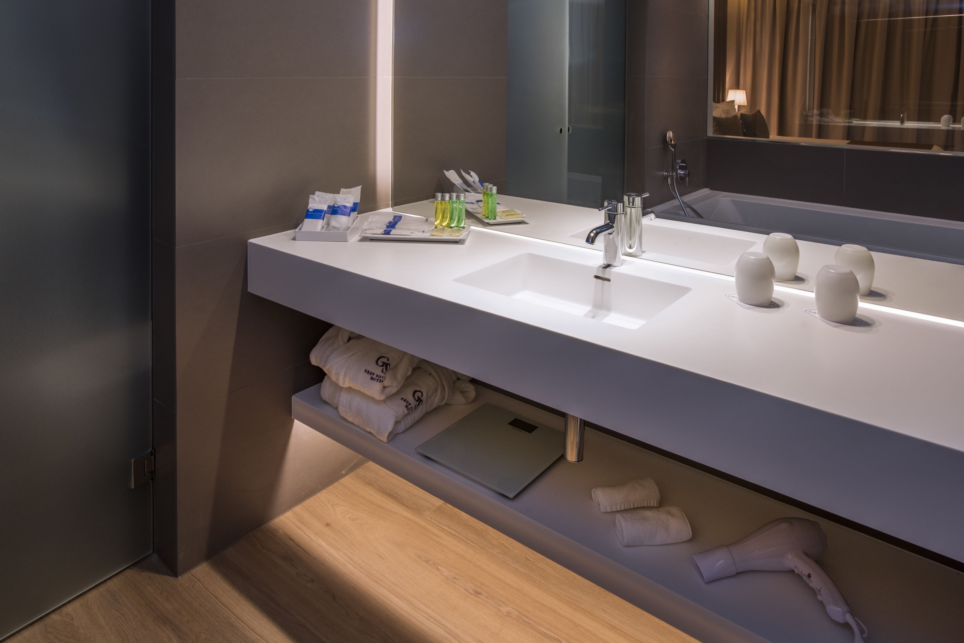 Un baño moderno con un espejo grande, dos lavabos y un perchero para toallas.
