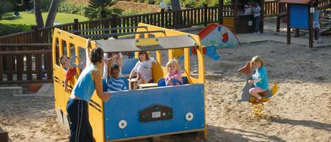 Un parque infantil con zona de juegos de arena y valla de madera.