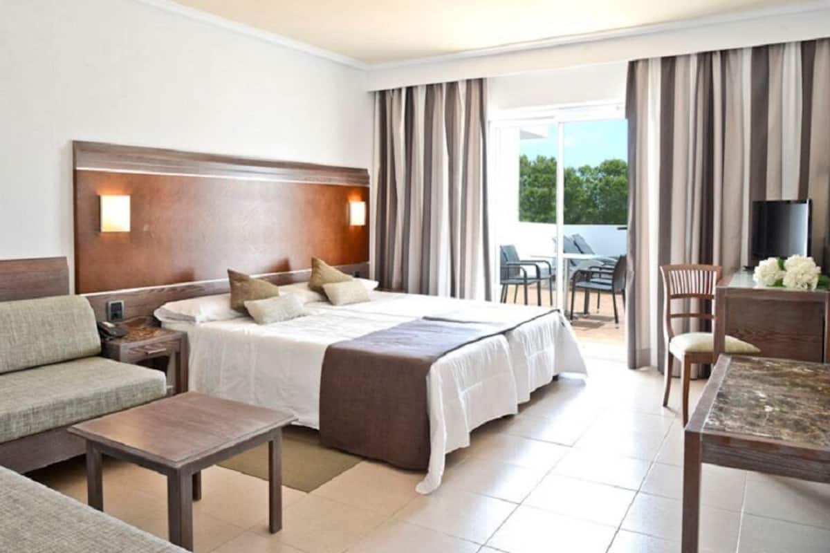 Una habitación de hotel con cama, sofá y una mesa de comedor.