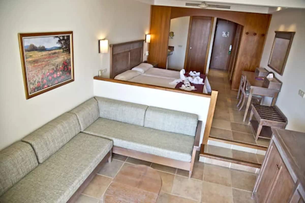 Habitación de hotel con sofá, cama, escritorio y baño a la vista a través de una puerta abierta.