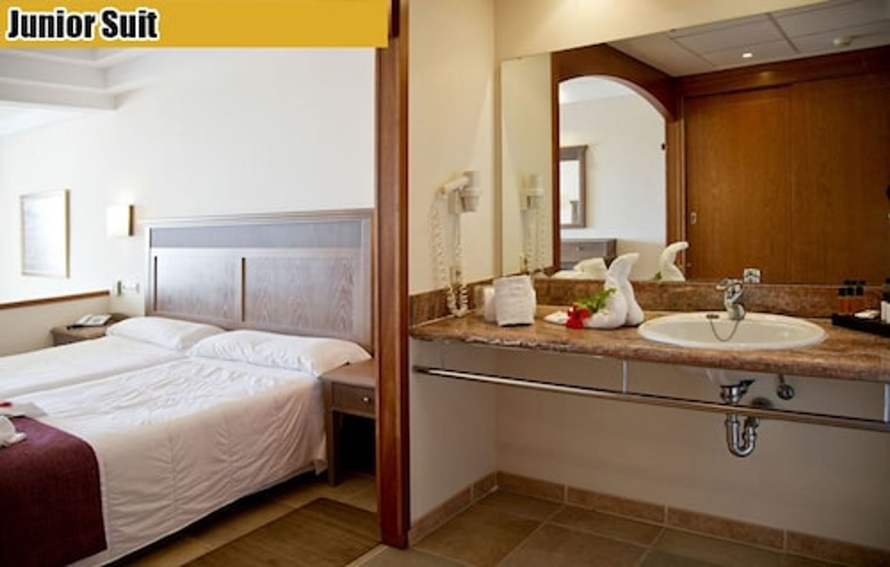 A hotel room with a double bed, a bathroom with a sink and mirror, and a telephone.