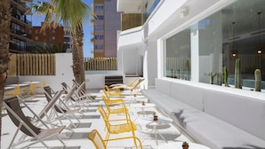 A rooftop lounge with sun loungers, a seating area, and a view of the cityscape. - Hotel whala!fun (Llucmajor)
